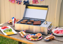 A stainless steel portable electric grill on a picnic table
