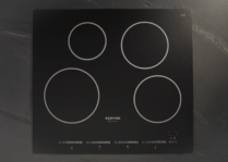 a 4 burner matte black cooktop on a black countertop