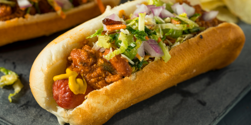Carolina-style slaw dog topped with chili, yellow mustard, and creamy coleslaw made with cabbage, carrots, and red onion, served in a soft bun.